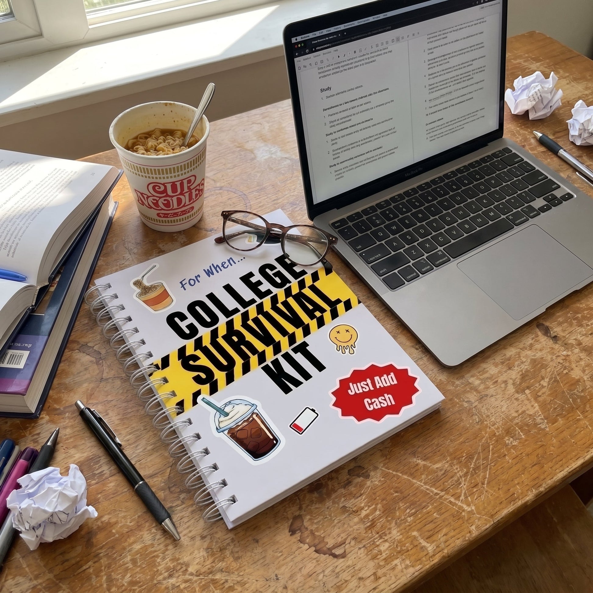 College Survival Kit on a dorm desk next to a laptop and cup noodles